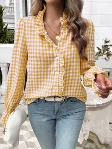 Detailed shot of a stylish yellow gingham ruffled long-sleeve blouse paired with classic blue jeans.