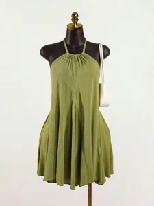 Detailed view of green halter pleated top, featuring sleeveless design and flowing fabric.