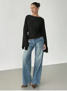 Women stylish black boat neck top with split long sleeves paired with loose jeans.