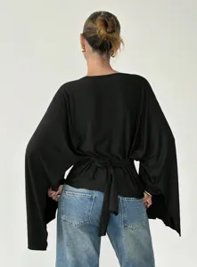 Elegant black long sleeve blouse detail showing stylish tie-back design and batwing sleeves.