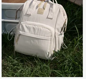 Beige waterproof mummy diaper backpack detail showing front zipper pocket and durable fabric.