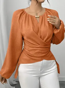 Elegante einfarbige Langarmbluse mit V-Ausschnitt, asymmetrischem Saum und schickem Perlendetail.