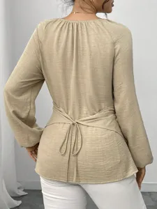 Rückansicht Detail der einfarbigen Langarmbluse mit Taillenband und unregelmäßigem Saum.