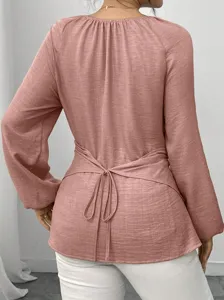 Rosa Langarmbluse mit Wickelgürtel und unregelmäßigem Saum für elegante und lässige Outfits.