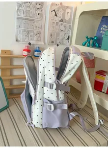 Vista dettagliata dello zaino a pois bianchi con spallacci viola e scomparti multipli.