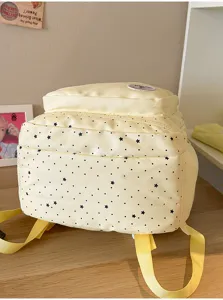 Detail shot of cute sweet style yellow backpack featuring allover black star print and pockets.