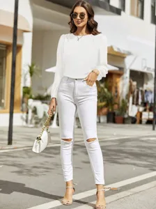 Elegant white crewneck long sleeve blouse paired with stylish white ripped skinny jeans for women.