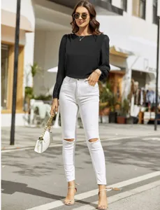 Women's crewneck long sleeve black blouse paired with white ripped skinny jeans for chic style.