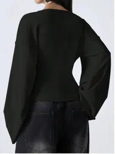 Elegant black V-neck drop shoulder flared sleeve top paired with stylish dark jeans.