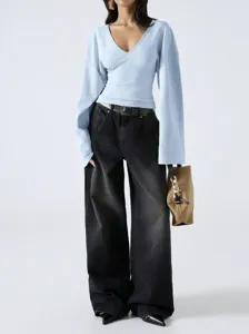 Detail view of the light blue V-neck top and black wide-leg jeans outfit worn by model.