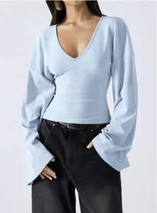 Close-up detail of light blue v-neck long flared sleeve top showing loose drop shoulder.
