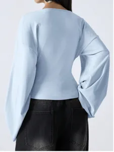 Back view of light blue top featuring dramatic bell sleeves and loose drop-shoulder fit detail.