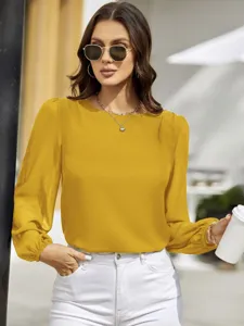 Close-up view of the yellow long-sleeve blouse, highlighting its fabric drape and round collar.