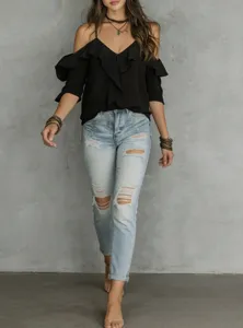 Detailed shot of the stylish black cold shoulder ruffle top paired with light wash ripped denim.