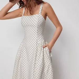 Detailed shot of vintage square neck polka dot dress featuring fitted waist and pockets.