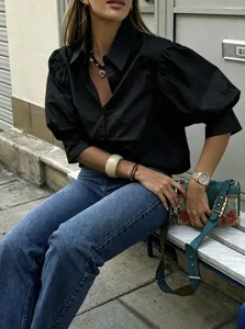 Detail view of the elegant black puff sleeve shirt, highlighting its classic design.