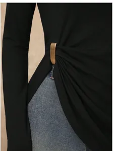 Detail view of black long sleeve top featuring stylish gold tone metal ring waist gathering.