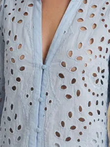 Close-up of light blue eyelet embroidered long sleeve button-down shirt with floral cutouts.