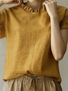Detailansicht des senfgelben Kurzarm-Tops mit Rüschenkragen und raffinierten Manschettendetails.