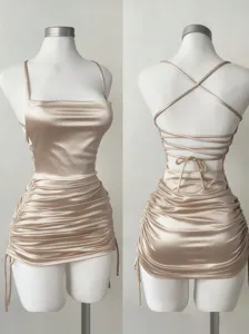 Detail view of champagne satin camisole dress, square neck, cross-back straps, and side ruched drawstrings.