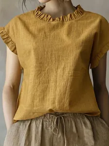 Nahaufnahme der senfgelben Bluse mit Rüschenkragen und kurzen Ärmeln, weiches Material.