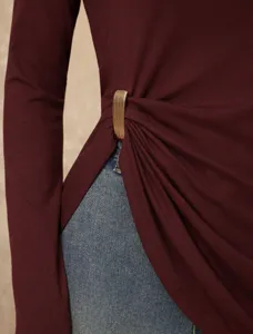 Detailed view of the elegant long sleeve top with unique metallic side waist buckle design.