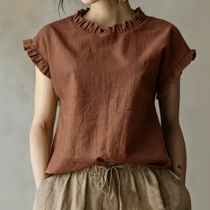 Nahaufnahme mit elegantem Rüschenkragen und kurzen Ärmeln des schicken braunen Tops.