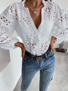 Detailed view of white hollow-out embroidered blouse featuring chic lantern sleeves and V-neck.