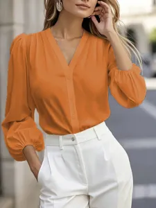 Close-up detail of the elegant V-neck lantern sleeve blouse in vibrant orange color.
