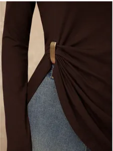 Detail shot of women's long sleeve top featuring stylish metallic buckle and side pleats.