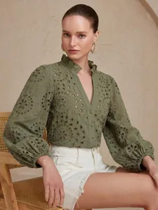 Detailed view of an olive green eyelet embroidered blouse with lantern sleeves and ruffle collar.