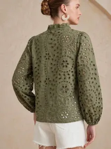 Detail view of the olive green eyelet embroidered blouse, featuring ruffle mock neck.