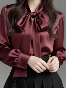 Detailed view of luxury burgundy satin bow tie blouse collar and exquisite cuff details.
