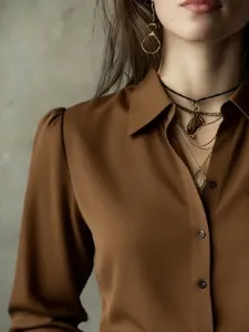 Elegant brown long sleeve women's shirt with button closure and layered fashion jewelry detail.