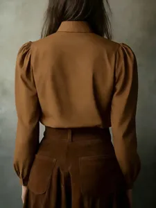 Back view detail of elegant brown long sleeve blouse with puff sleeves and matching skirt.
