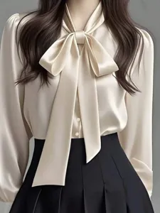 Elegant satin blouse detail featuring a chic ribbon bow tie and smooth drape for women.