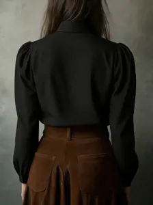 Detail shot of the elegant black long sleeve blouse with puff sleeves showing the back design.