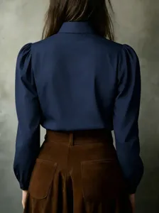 Back view detail of a solid dark blue long sleeve blouse with elegant puffed shoulders.