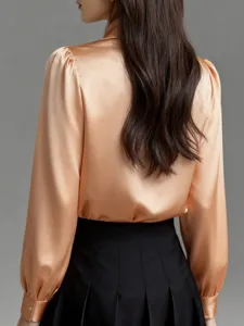 Back detail of elegant satin blouse with long sleeves and draping fabric, paired with skirt.