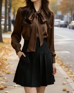 Close-up of elegant brown long sleeve bow-tie blouse paired with black pleated skirt for commute.
