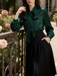 Elegant dark green silk blouse with bow tie collar, detailed shot showing luxury commute style.