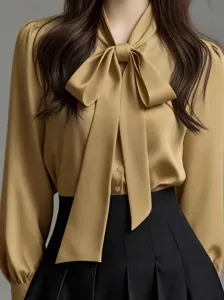 Close-up of elegant khaki pussy-bow blouse detail with graceful neck bow and buttons.