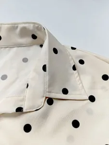 Close-up detail of women's long sleeve polka dot shirt, elegant lapel collar, soft fabric.