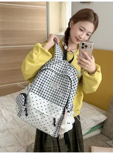 Vue détaillée du sac à dos à carreaux et pois noirs et blancs avec un joli pendentif en peluche.