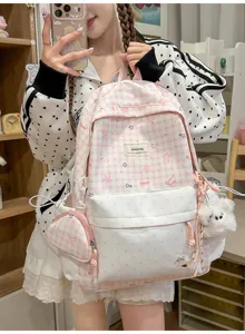 Détail de sac à dos rose à carreaux avec jolies poches à pois et joli pendentif doux.