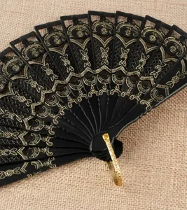 Gros plan detail de l'éventail pliable en dentelle noire avec motif doré et anneau.