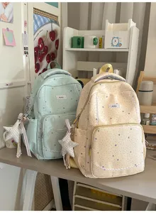 Detail view of stylish canvas school backpacks with star patterns and cute pendants.