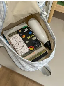 Vue plongeante sur l’intérieur du sac à carreaux bleu clair, avec doublure beige, zip et compartiments