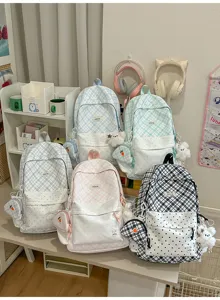 Cinq sacs à dos à carreaux, bleu, menthe, gris, rose et noir, avec des peluches sur une table