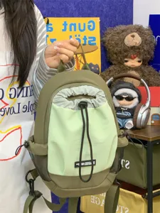 Nahaufnahme des grünen Mini-Outdoor-Rucksacks mit Kordelzugverschluss und Stoffdetails.